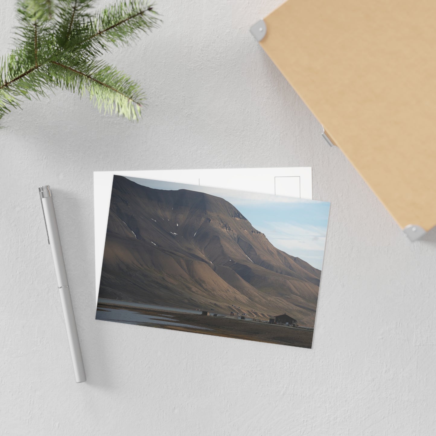 Postcard of Hiorthfjellet laying on a white desk with a pen next to it