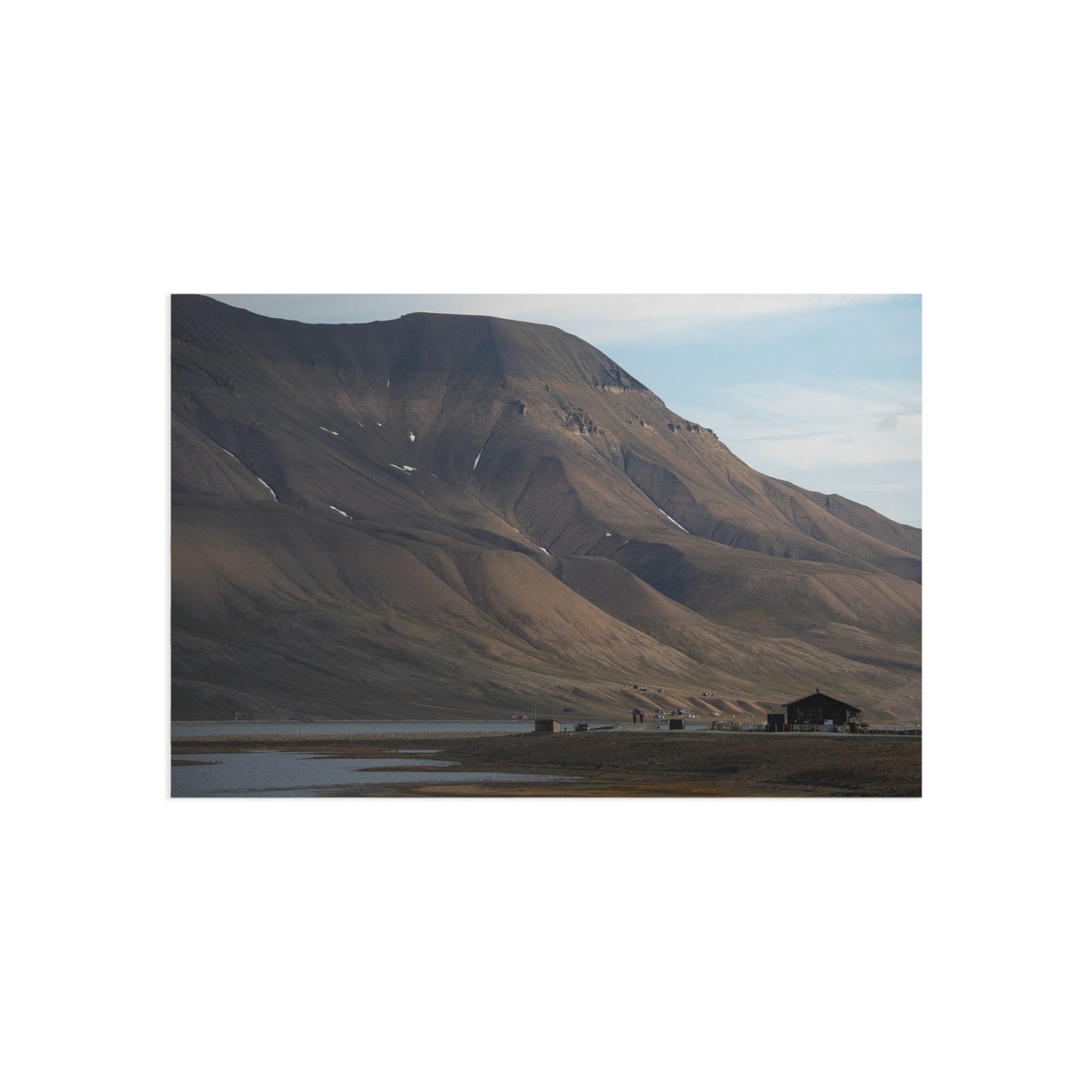 Postcard of Hiorthfjellet: a very tall mountain that has a flat plateau on top, with a river next to it on the bottom, and a small road going through the river.