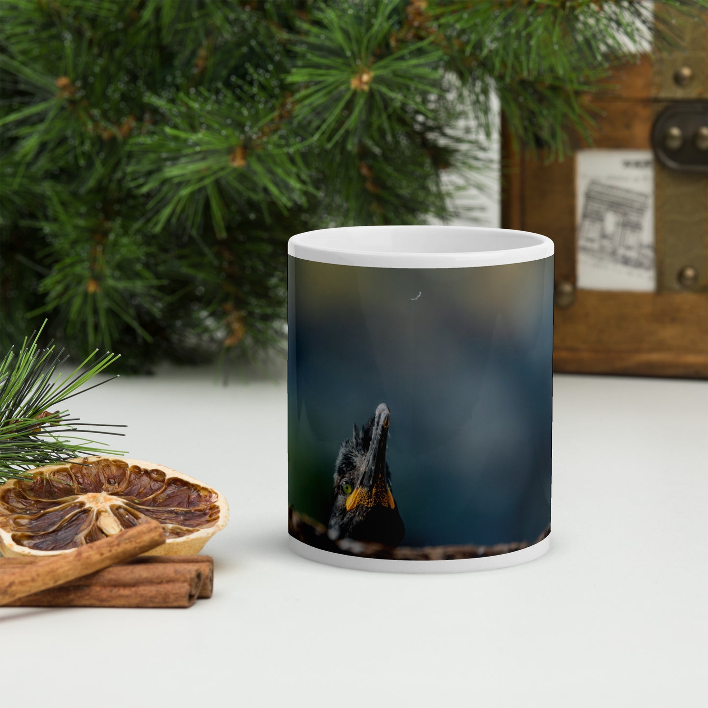 White mug wit a print of a shag peeking from behind a rock. Only the shag's face is visible, and he seems to be looking at a falling feather. The background is blue and yellow blurry.